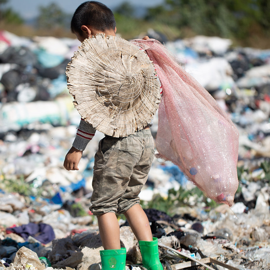 Kind vor Müllhaufen
